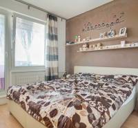 Schlafzimmer in einer 3-Zimmer-Wohnung mit dekorativer Wand, Regal und Bett, Boden mit Holzdekor.