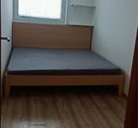 Schlafzimmer in einer 2-Zimmer-Wohnung mit Bett, Regalen und Boden in Holzoptik.