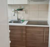 Küche mit weißen Schränken und Edelstahlspüle in einer 2-Zimmer-Wohnung.