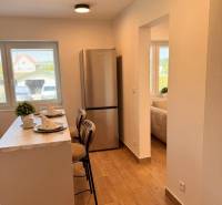 Küche in einer 2-Zimmer-Wohnung mit Bar, Holzboden und Kühlschrank.