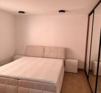 Helles Schlafzimmer einer Zweizimmerwohnung mit Holzboden und bequemem Bett.