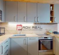 Küche mit Holzdekorboden, eingebauten Geräten und Wandschränken in einer 2-Zimmer-Wohnung.