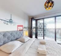 Schlafzimmer in einer 2-Zimmer-Wohnung mit Balkon und Flugzeugdekor an der Wand.