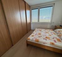 Schlafzimmer in einer 3-Zimmer-Wohnung mit großem Schrank und Bett, Boden mit Holzdekor.