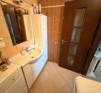 Badezimmer in einer 3-Zimmer-Wohnung mit weißen Möbeln und dunklen Türen.