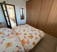 Schlafzimmer in einer 3-Zimmer-Wohnung mit Bett, Einbauschrank und Boden mit Holzdekor.