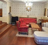 Wohnzimmer in einem Einfamilienhaus mit roten Möbeln und einem Fernseher auf einem Boden mit Holzdekor.