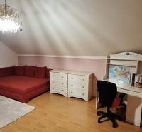 Schlafzimmer mit Möbeln, rotem Sofa, Schreibtisch und Holzboden in einem Einfamilienhaus.