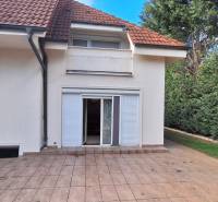 Ein Einfamilienhaus in Komárno mit Terrasse, Garten und weißen Fensterläden.