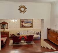 Luxuriöses Interieur eines Einfamilienhauses mit Holzelementen, Sofa und Kunstwerken an den Wänden.