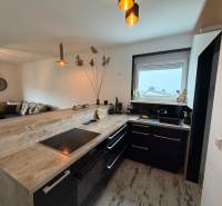 Küche mit schwarzen Möbeln, Bartresen und Boden mit Holzdekor in einer 3-Zimmer-Wohnung.