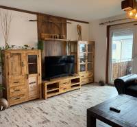 Wohnzimmer in einer 3-Zimmer-Wohnung mit Holzmöbeln und Boden in Holzoptik.