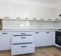 Küche in einer 3-Zimmer-Wohnung mit weißen Schränken und einem Boden in Holzoptik.