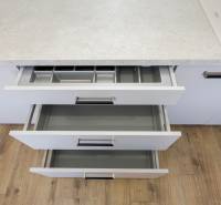 Öffnen von Küchenschubladen in einer 3-Zimmer-Wohnung mit Arbeitsplatte und Boden in Holzoptik.