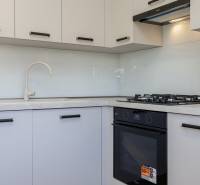 Küche in einer 3-Zimmer-Wohnung mit Herd und weißen Schränken.