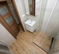 Ein Badezimmer mit Badewanne, Waschbecken und einem Boden in Holzoptik in einer 3-Zimmer-Wohnung.