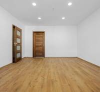 Ein Zimmer in einer 3-Zimmer-Wohnung mit einem Boden in Holzoptik und Holztüren.