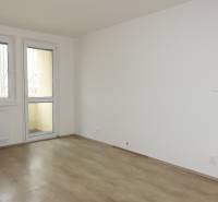 Ein Zimmer mit einem Holzboden in einer 3-Zimmer-Wohnung, Tisch und Stuhl.