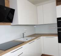 Eine Küche mit weißen Schränken und Geräten, ergänzt durch einen Bodenbelag in Holzoptik in einer 3-Zimmer-Wohnung.