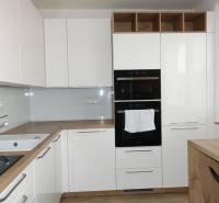 Moderne Küche mit weißen Schränken und Holzboden in einer 3-Zimmer-Wohnung.