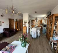 Wohnzimmer mit Küche in einem Einfamilienhaus, Boden mit Holzdekor, Blumen auf dem Tisch.