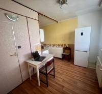 Küche in einer 3-Zimmer-Wohnung mit Schreibtisch, Kühlschrank und Holzboden.