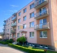 Ein vierstöckiges Wohngebäude in Moravské Lieskové mit Balkonen und Parkmöglichkeiten vor dem Gebäude.