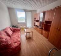 Ein Zimmer in einer 3-Zimmer-Wohnung mit einem Sofa, Schränken und einem Tisch auf einem hellen Boden.