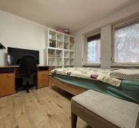 Ein Zimmer in einer 2-Zimmer-Wohnung mit einem Bett, einem Schreibtisch und einem Boden mit Holzdekor.