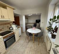 Küche in einer 2-Zimmer-Wohnung mit rundem Tisch, Pflanzen und Geräten.