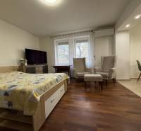 Schlafzimmer in einer 2-Zimmer-Wohnung mit Holzboden und bequemen Sesseln.