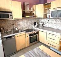 Küche in einer 3-Zimmer-Wohnung mit Holzdekor-Schränken, Trockner und Ofen.