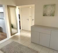 Diele in einer 3-Zimmer-Wohnung mit weißen Möbeln, einem Spiegel und einem Boden mit Holzdekor.