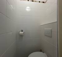 Badezimmer in einer Einzimmerwohnung mit weißen Fliesen und einer Wand mit dekorativem Streifen.