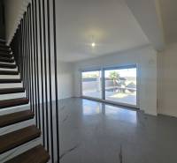 Wohnzimmer in einer Villa mit modernen Treppen und großen Fenstern.