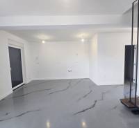 Ein geräumiger Raum in der Villa mit weißen Wänden und einem grauen Boden mit Dekor.