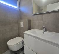 Badezimmer in der Villa mit Waschbecken, hängender Toilette und großem Spiegel.