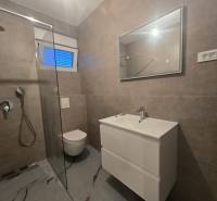 Badezimmer in der Villa mit Toilette, Duschkabine und Waschbecken, Fliesen mit Steinmuster.