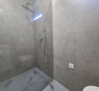 Duschkabine mit transparenter Abtrennung und grauen Fliesen in der Villa.