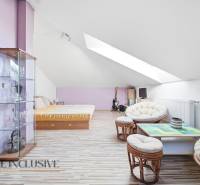 Dachzimmer in einem Einfamilienhaus mit Holzboden, Möbeln und Dachfenstern.