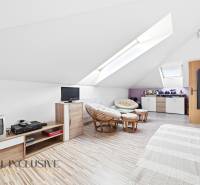 Ein Dachzimmer in einem Einfamilienhaus mit Sesseln und einem Boden in Holzoptik.