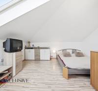 Dachbodenschlafzimmer mit Fernseher, Bett und Schränken in einem Einfamilienhaus.