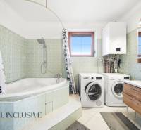 Badezimmer mit Badewanne, Dusche, Waschmaschine und Trockner in einem Einfamilienhaus.