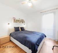 Ein Schlafzimmer in einem Einfamilienhaus mit einem Bett, Holzboden-Dekor und einem Fernseher an der Wand.