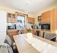 Küche in einem Einfamilienhaus mit Holzmöbeldekor und Ausstattung, Blumendekoration auf dem Tisch.