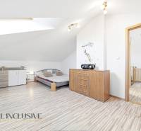 Helles Schlafzimmer mit Holzboden, Kommode und Bett in einem Einfamilienhaus.