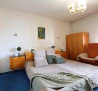 Schlafzimmer mit großem Bett, Holzschränken und Sessel in einem Einfamilienhaus.