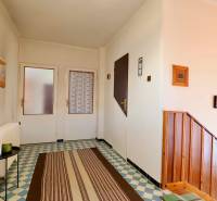 Ein Einfamilienhaus mit gemusterten Fliesen, Holztreppen und einfacher Wanddekoration.