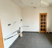 Ein leerer Raum in einer 2-Zimmer-Wohnung, dunkler Fliesenboden, weiße Wände, Holztüren.