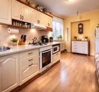 Küche in einer 2-Zimmer-Wohnung mit Holzboden, heller Küchenzeile und Pflanzen.